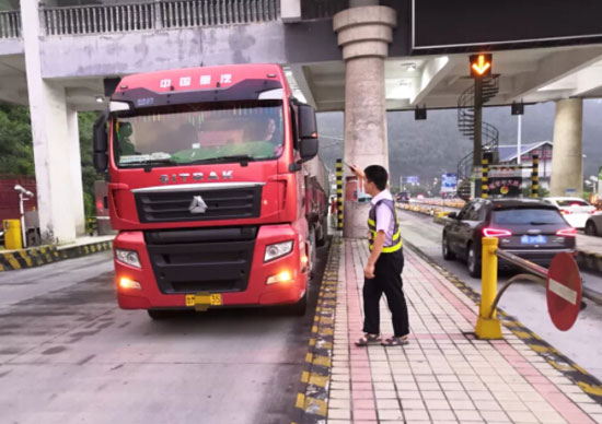 圖為收費(fèi)班長引導(dǎo)該車駛出收費(fèi)站